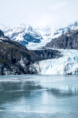 A glacier, a river of ice, winds down to the sea through steep mountainous terrain