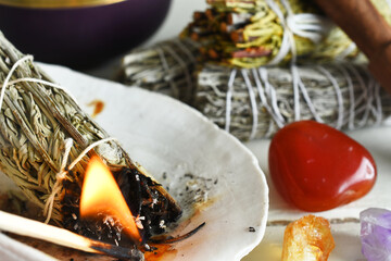 A close up image of a burning white sage smudge bundle and several healing energy crystals.