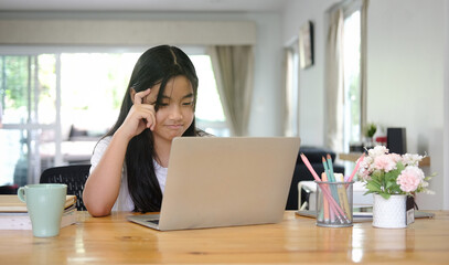 Fototapeta premium Asian girl student using digital tablet for online lesson at home.