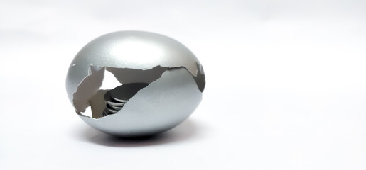 Closeup of broken Silver Egg shell isolated in a White background with selective focus and copy space symbolizing the concept of retirement money, investment , savings , pension , fixed deposit.