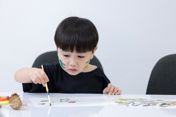 Happy little Asian kid at the table draw with water color Learning and education of kid.