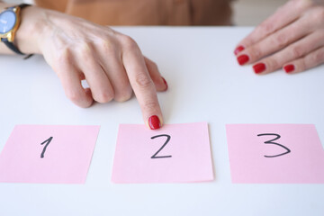 Woman showing index finger to sticker with number 2