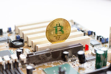 Golden Bitcoin on the circuit board. Mining cryptocurrency using computer elements. Golden fever.
