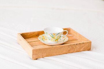 On the bed is a wooden tray with a cup and coffee