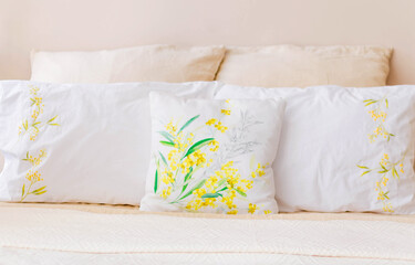 There are many pillows of white and beige colors on the bed.