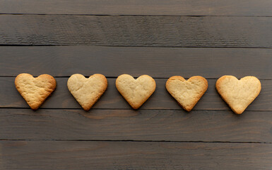 Row of five heart cookies on wooden brown background horizontal photo