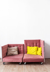 The pink sofa is in two parts and stands against a white wall.