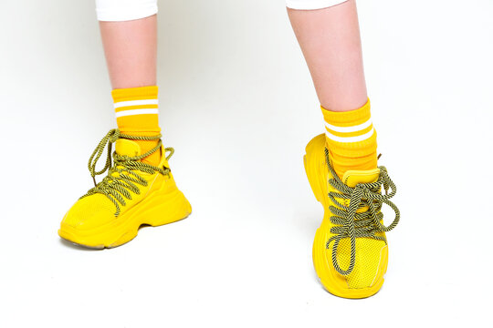 Teenage Female Legs In Yellow Sneakers On A White Background