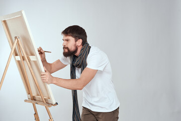 male artist painting on easel art lifestyle light background