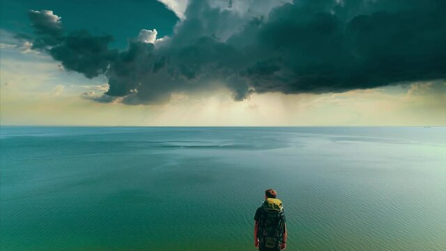 The traveler with bag standing on the mountain edge on the seascape background