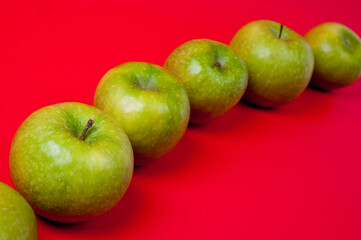 Large green apples, ripe and juicy. Photographed against a uniform red background.