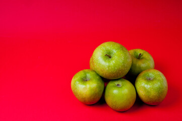 Large green apples, ripe and juicy. Photographed against a uniform red background.