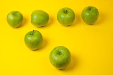 Large green apples, ripe and juicy. Photographed against a uniform yellow background.