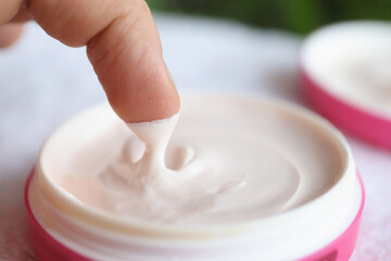 Man taking out nourishing cream from jar closeup