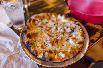 Tasty cheese pizza and a glass of water on vintage-looking table