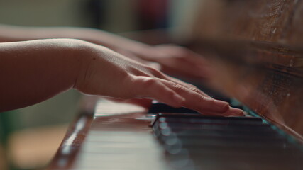 Female hands playing piano indoors. Close up of musician playing melody.