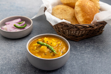Masala Aloo Sabzi or Indian potato gravy served with fried puri or Poori with sliced onion and green chilly 