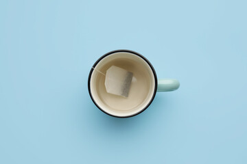 Cup with tea bag on color background