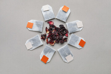Tea bags and dry leaves on grey background