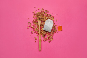 Tea bag, spoon and dry rose petals on color background