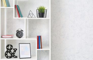 Modern shelf unit with books and decor near light wall