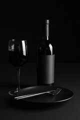 Stylish table setting with glass and bottle of wine on dark background