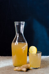 Ginger and lemon drink - kombucha in a bottle on a dark wooden background. Ginger Ale is a homemade organic probiotic drink with lemon and ginger. copy space.