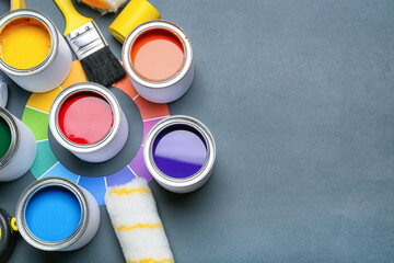 Cans of paints and painter's supplies on color background