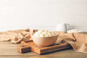Bowl with cottage cheese on wooden background