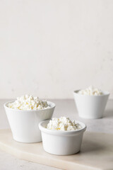Bowls with cottage cheese on light background