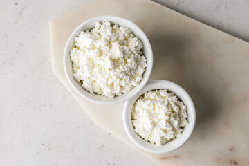 Bowls with cottage cheese on light background