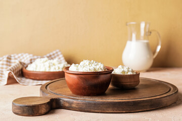Bowls with cottage cheese on color background