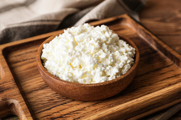 Bowl with cottage cheese on wooden background
