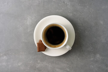 Obraz na płótnie Canvas Cup of black coffee with chocolate on grey concrete background