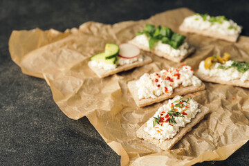 Crispbreads with cottage cheese and vegetables on dark background