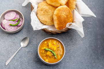 Masala Aloo Sabzi or Indian potato gravy served with fried puri or Poori with sliced onion and green chilly 