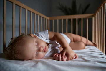 Cute baby sleeps at night in a cradle for babies without a canopy and bumpers. Safe sleep in a...