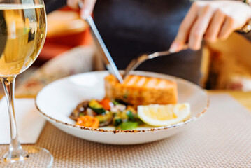 woman eating salmon steak with roasted vegetables