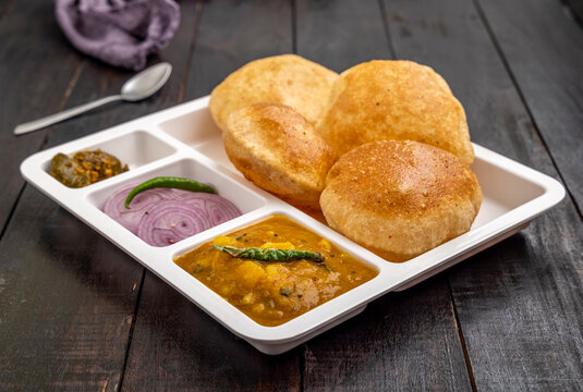 Masala Aloo Sabzi or Indian potato gravy served with fried puri or Poori with sliced onion and green chilly 