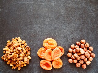 Dried fruits with nuts on black background top view. Hazelnuts, dried apricots, raisins. Healthy food and snack. Flat lay. Place for text