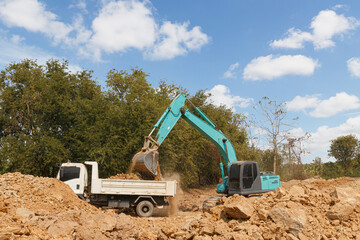 Obraz premium Crawler Excavator digging the soil into a truck ,In the construction site area outdoor .