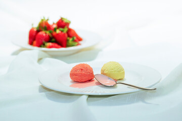 Two ice cream scoops with a spoon and strawberries: food concept.