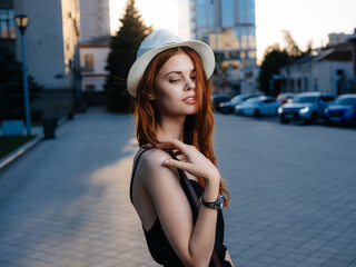 Elegant woman in black dress near the building on the street at sunset