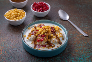 Indian tasty street food Dahi Bhalla or  Dahi Vada garnished with tamarind sauce and pomegranate seeds 
