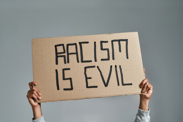 Placard with Racism is Evil inscription held by man