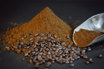 Ground coffee drips out of the scoop. Coffee powder and beans on black background.