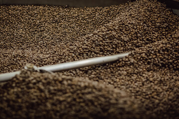 Coffee beans are mixed closeup. Coffee roasting machine. Freshly roasted coffee beans are cooled. 