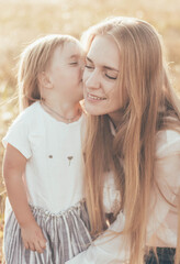 Obraz premium little daughter kissing mom in the park