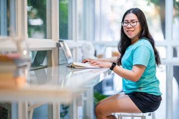 Happy of asian freelance people businessfemale wearing smartwatch casual working with laptop computer and book with coffee cup and smartphone in at the cafe, Business Lifestyle communication concept