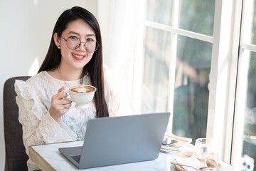 Happy of asian freelance people businessfemale hold a coffee cup mug casual working with laptop computer with Notebook and smartphone in coffee shop,Business Lifestyle communication concept